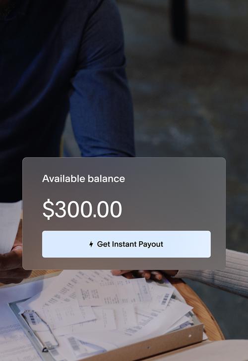 Two people reviewing paperwork at a table. Balance card UI showing `Available balance $300.00` with button `Get instant payout`.